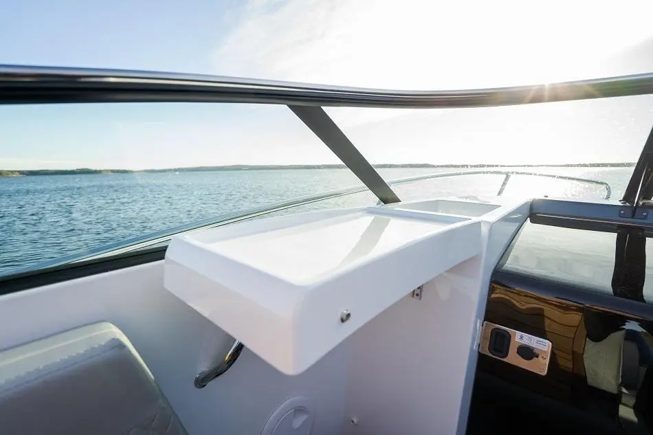 View from a boat showing a sleek white dashboard against a sparkling water backdrop and sunny sky.